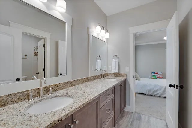 a en suite bathroom with a granite countertop double vanity sink and a mirror