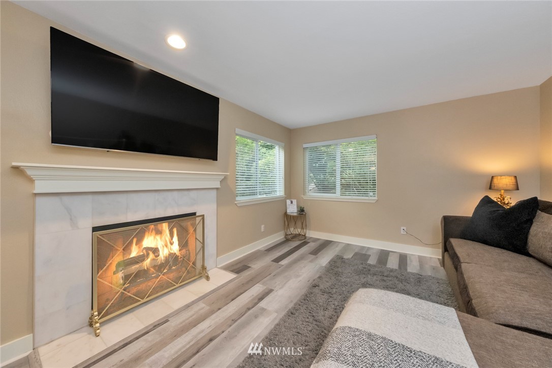 455 Newport Way Northwest, Unit 302 Issaquah, WA 98027 - Photo 3 of 17 a living room with a fireplace a flat screen tv and a window