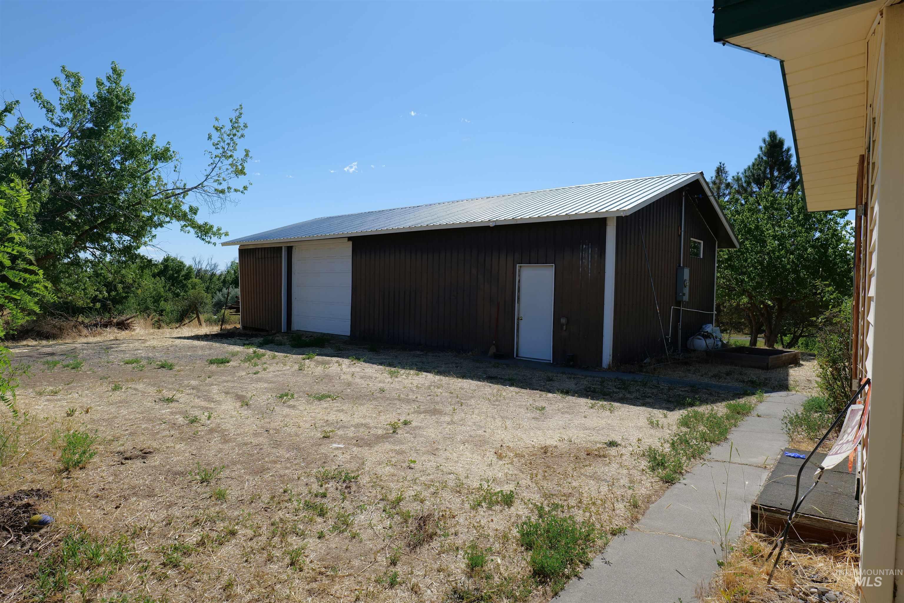 1485 East 9th Street Weiser, ID 83672 - Photo 14 of 18 Metal utility building with a white roll-up door, side entry door, and corrugated metal roof