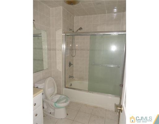 7504 Hana Road Edison, NJ 08817 - Photo 8 of 10 a bathroom with a granite countertop shower a toilet and a sink