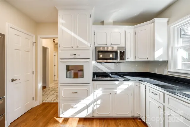 a kitchen with white cabinets and appliances