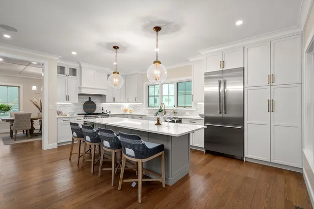 a kitchen with stainless steel appliances granite countertop a sink a stove a refrigerator and island with wooden floor