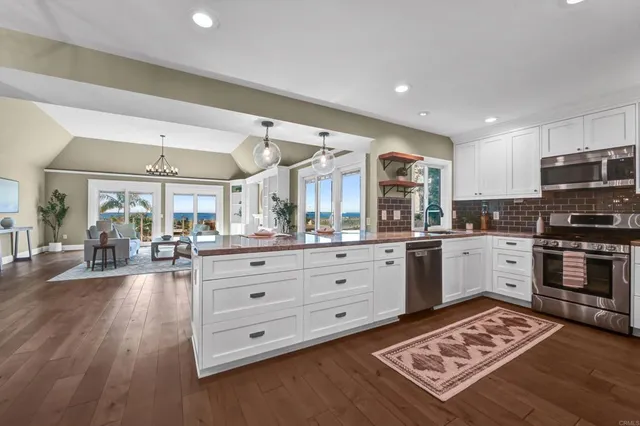 a large white kitchen with stainless steel appliances granite countertop a stove and cabinets