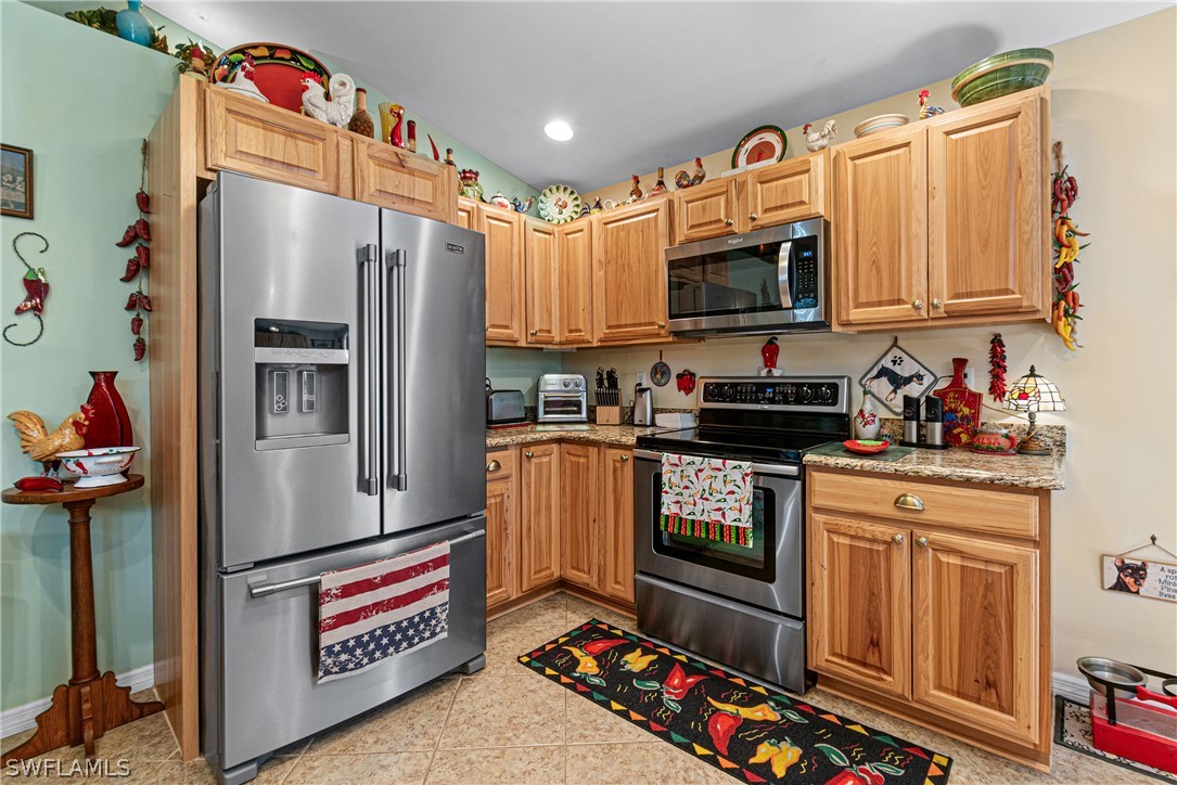 9701 Baycrest Terrace Lehigh Acres, FL 33936 - Photo 22 of 50 a kitchen with stainless steel appliances a refrigerator sink stove and cabinets