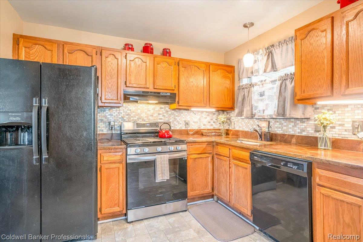 3582 Swanson Street Wayne, MI 48184 - Photo 12 of 30 Kitchen featuring black appliances, backsplash, pendant lighting, under cabinet range hood, and light countertops