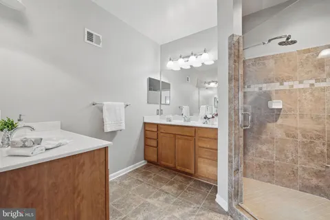 a bathroom with a sink vanity granite tub shower and a mirror