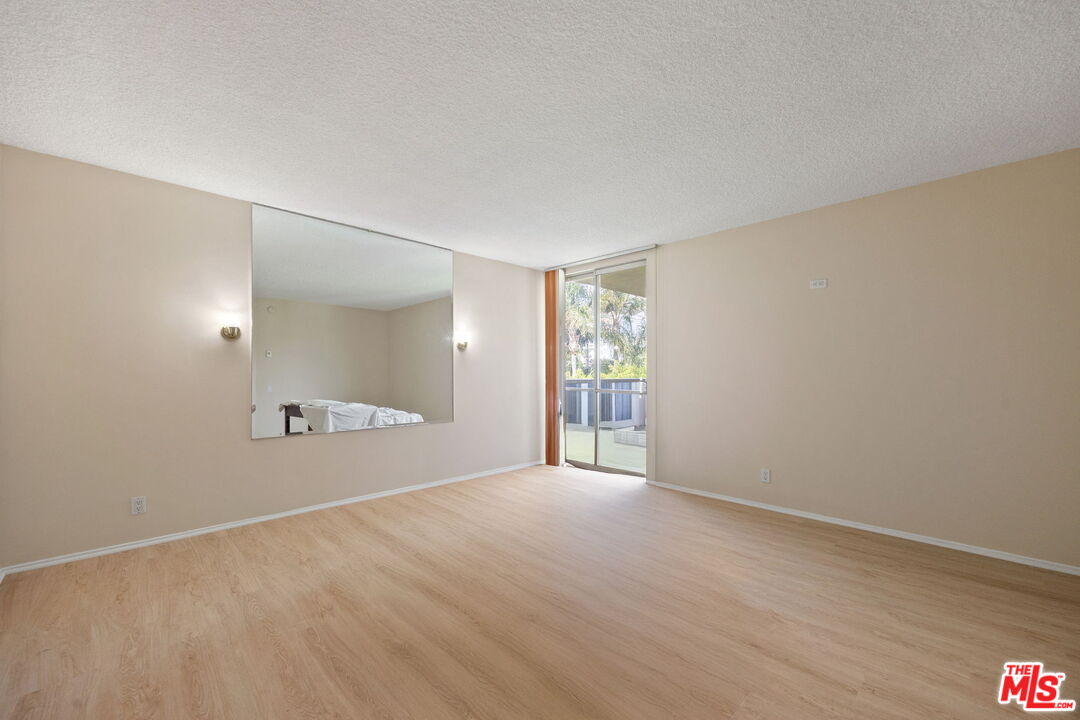 1025 North Kings Road, Unit 313 West Hollywood, CA 90069 - Photo 14 of 18 a view of an empty room with wooden floor and a window