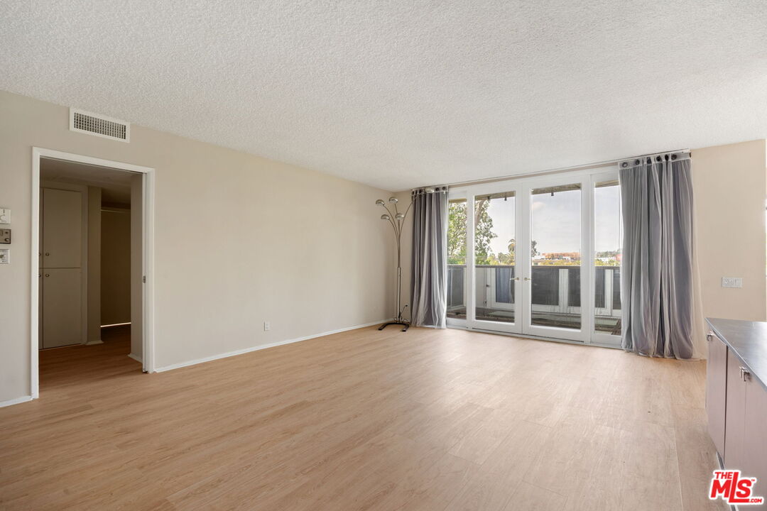 1025 North Kings Road, Unit 313 West Hollywood, CA 90069 - Photo 7 of 18 a view of an empty room with wooden floor and a window