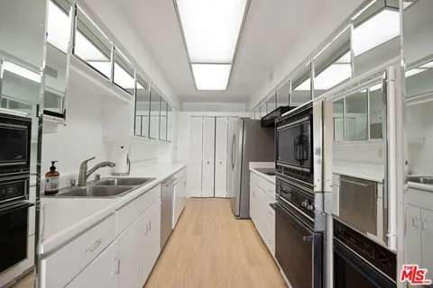 a kitchen with kitchen island a counter top space a sink a refrigerator and cabinets
