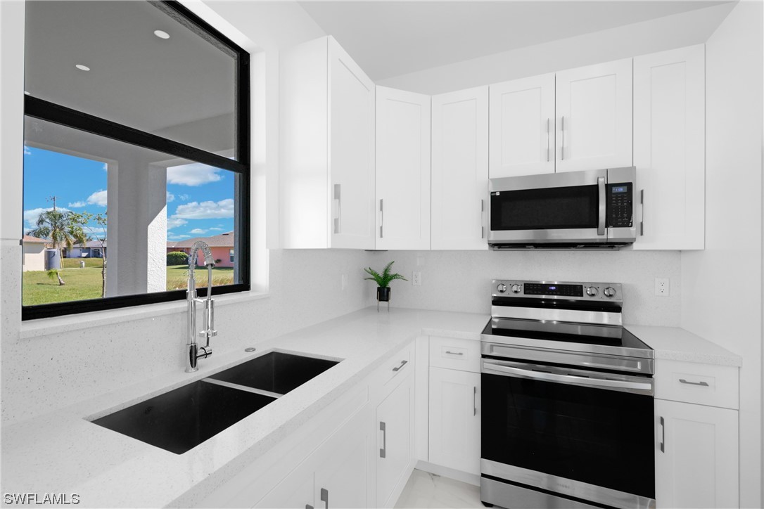 2917 Nelson Road North Cape Coral, FL 33993 - Photo 20 of 25 a kitchen with stainless steel appliances a stove a microwave and sink