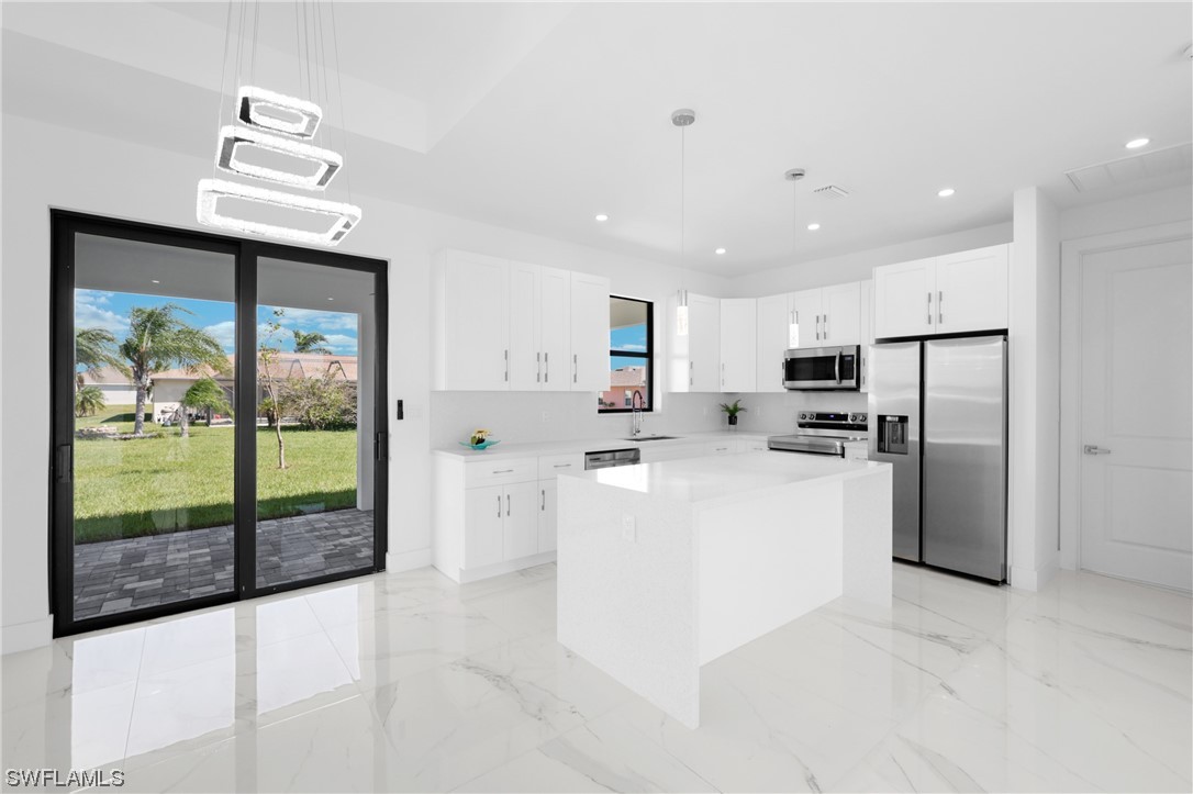 2917 Nelson Road North Cape Coral, FL 33993 - Photo 7 of 25 a large white kitchen with refrigerator a sink and cabinets