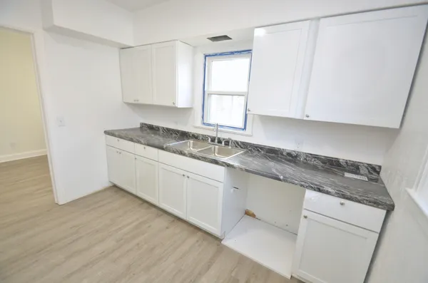 a kitchen with granite countertop white cabinets and a sink