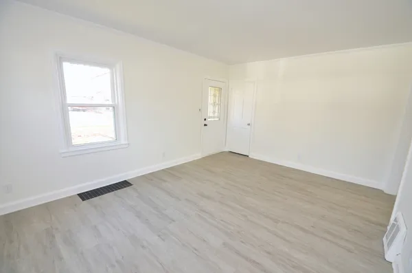 an empty room with wooden floor and windows
