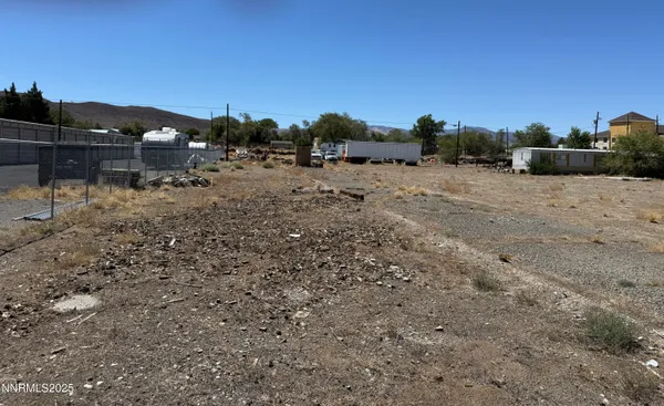 a view of a dry yard with wooden fence