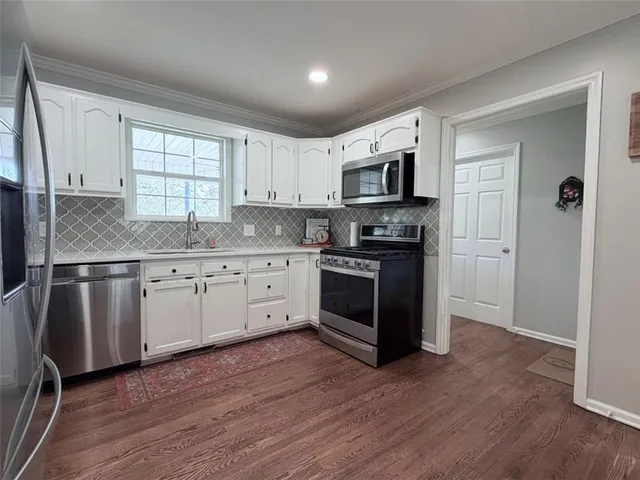 a large white kitchen with kitchen island a sink dishwasher a refrigerator and cabinets