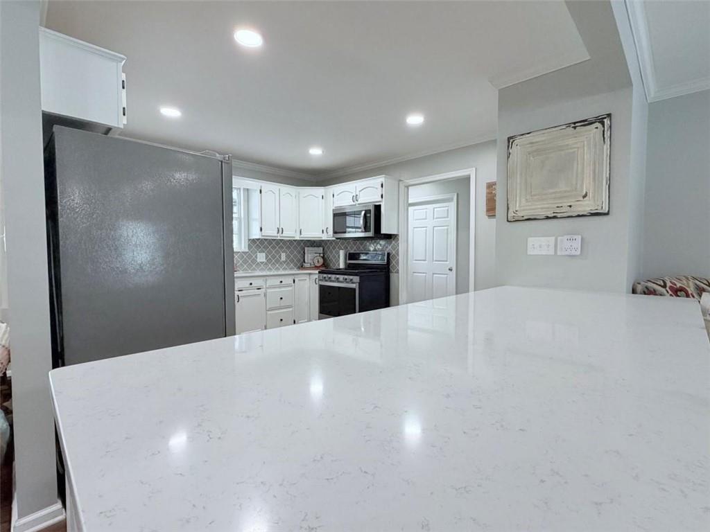 2053 Buttermilk Road Southwest Cave Spring, GA 30124 - Photo 30 of 50 a large white kitchen with kitchen island a sink dishwasher a refrigerator and cabinets