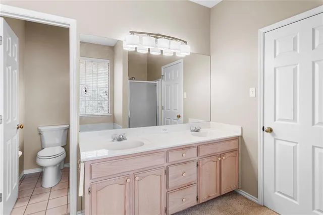 a spacious bathroom with a granite countertop sink a toilet and a mirror