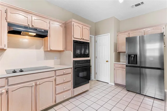 a kitchen with white cabinets and refrigerator