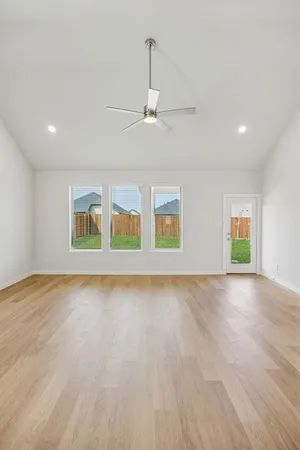 a view of an empty room with window and wooden floor