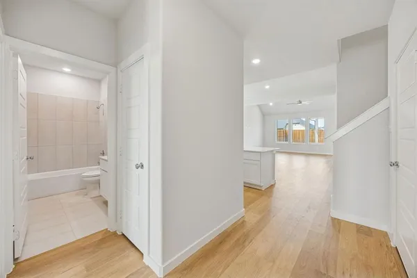 a view of a hallway with wooden floor and a bathroom