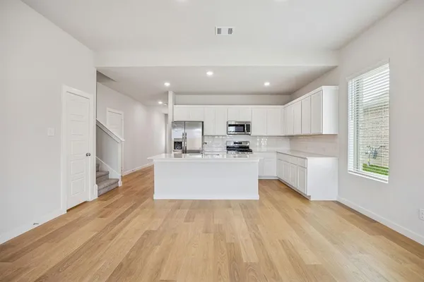 a large kitchen with kitchen island a sink a center island stainless steel appliances and a window