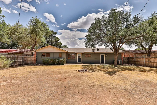 a backyard of a house with table and chairs a large tree