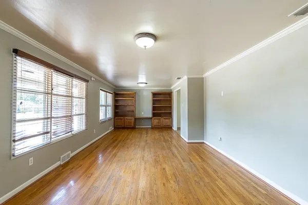 a view of an empty room with wooden floor and a window