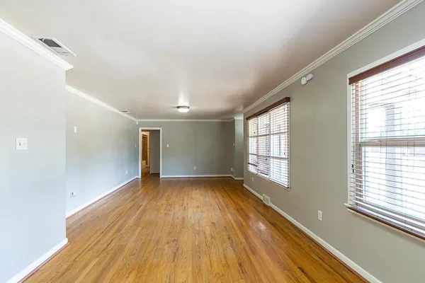 a view of an empty room with wooden floor and a window