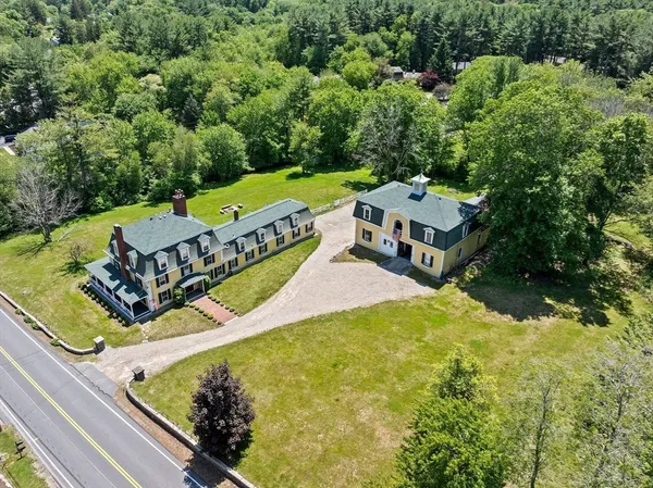 an aerial view of a house with swimming pool and large trees