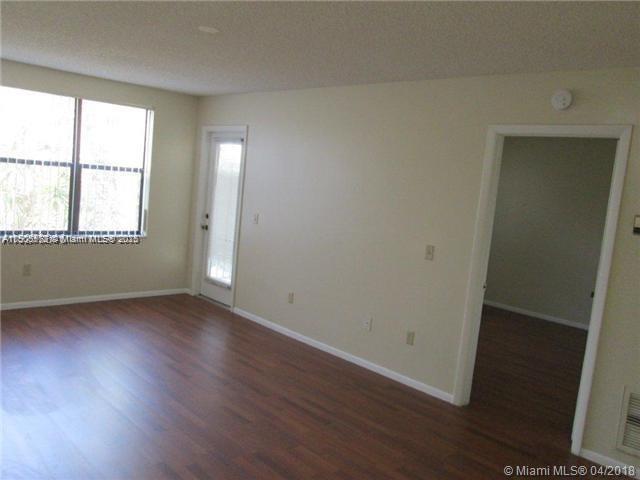 4541 West McNab Road, Unit 16 Pompano Beach, FL 33069 - Photo 3 of 23 an empty room with wooden floor and windows