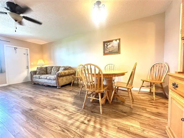 a living room with furniture and a dining table with wooden floor