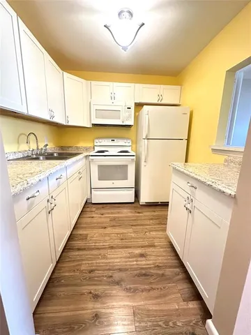 a kitchen with granite countertop white cabinets and white appliances