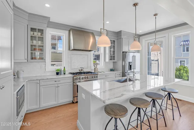 a kitchen with stainless steel appliances granite countertop a stove a sink a refrigerator a dining table and chairs