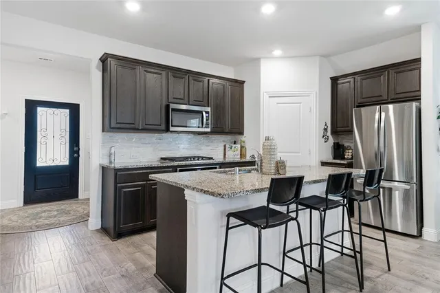 a kitchen with stainless steel appliances granite countertop a stove top oven a sink and a refrigerator