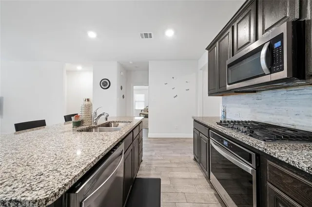 a kitchen with stainless steel appliances granite countertop a sink stove and microwave