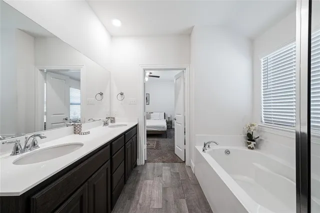 a en suite bathroom with a double vanity sink a mirror and a bathtub