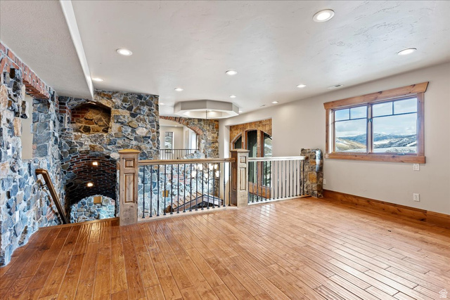 246 Woods Creek Road Morgan, UT 84050 - Photo 35 of 69 Wood-finish flooring, recessed ceiling lighting, stone accent walls, wood trim window, and wrought iron railings