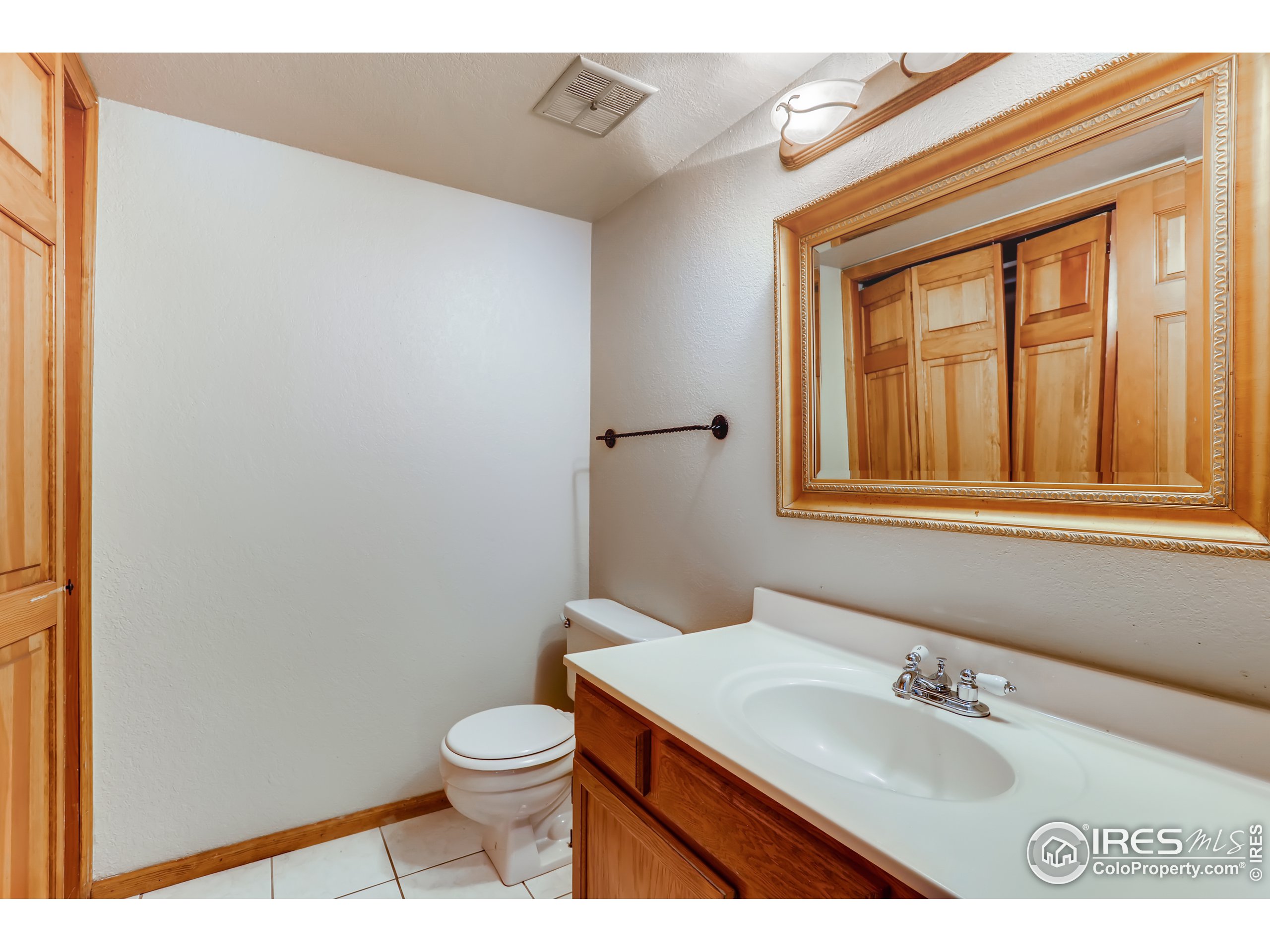 2315 Ranch Drive Westminster, CO 80234 - Photo 8 of 28 a bathroom with a toilet a sink a mirror and a window