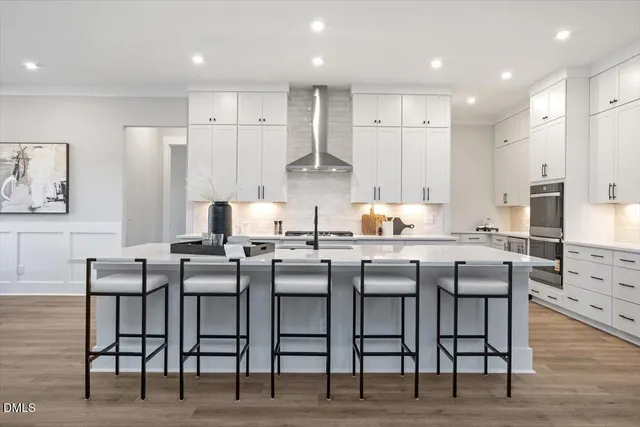 a kitchen with stainless steel appliances granite countertop a stove a sink a refrigerator white cabinets with a dining table and chairs