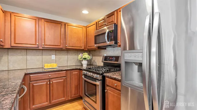 a kitchen with stainless steel appliances granite countertop wooden cabinets a stove a sink and a window