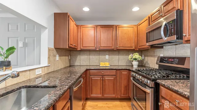 a kitchen with stainless steel appliances granite countertop a sink stove and cabinets