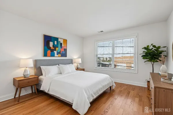 a bedroom with a bed a dresser and a potted plant next to a window