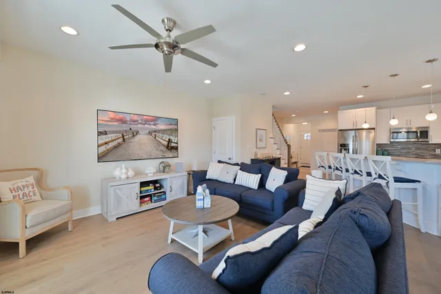 a living room with furniture kitchen view and a wooden floor
