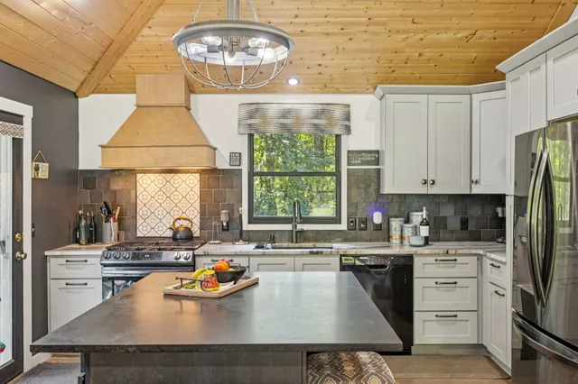 a kitchen with a refrigerator a stove a dining table and chairs with the outer view