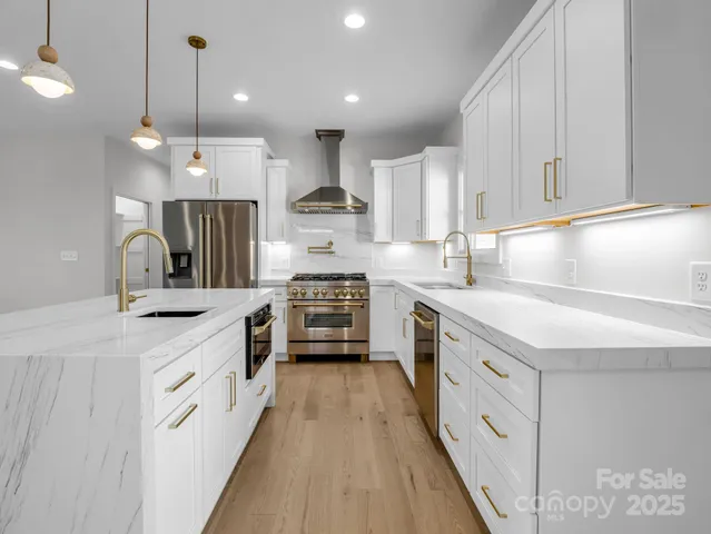 a kitchen with stainless steel appliances granite countertop a stove and a wooden floor