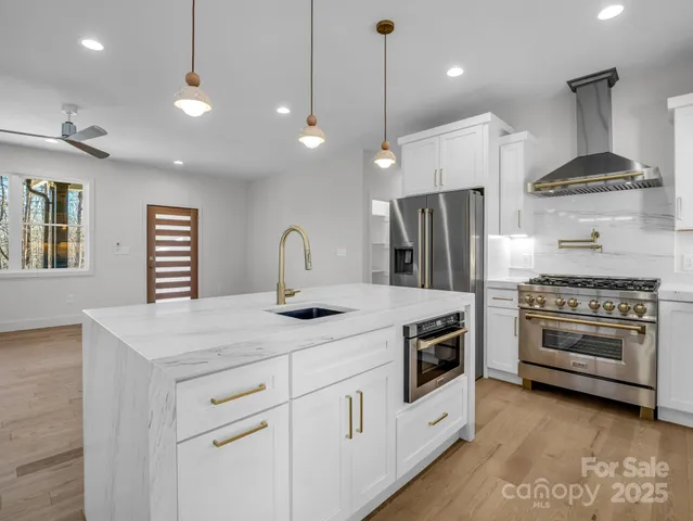 a kitchen with stainless steel appliances granite countertop a sink a stove and a refrigerator