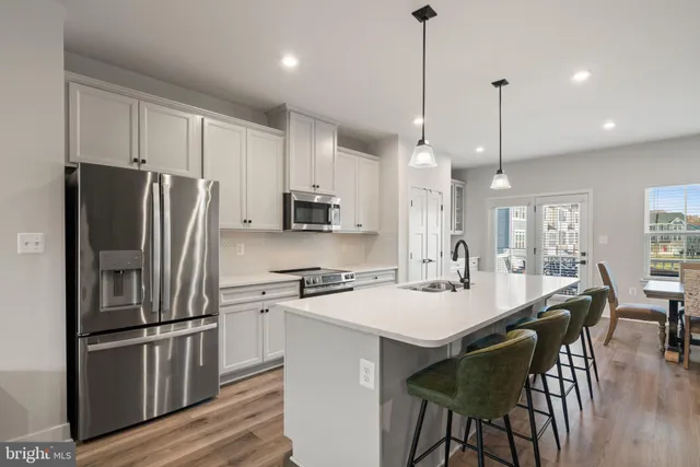 a kitchen with stainless steel appliances a table chairs stove and refrigerator