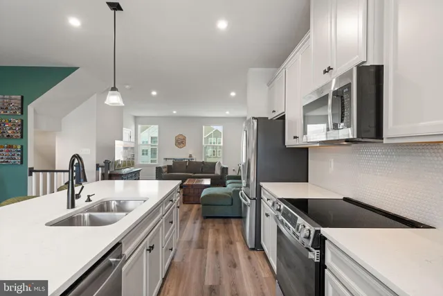 a kitchen with stainless steel appliances granite countertop a sink a stove and a wooden floors
