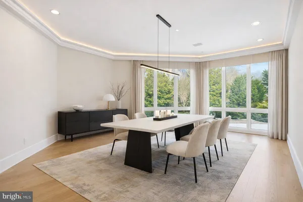 a dining room with wooden floor and large windows