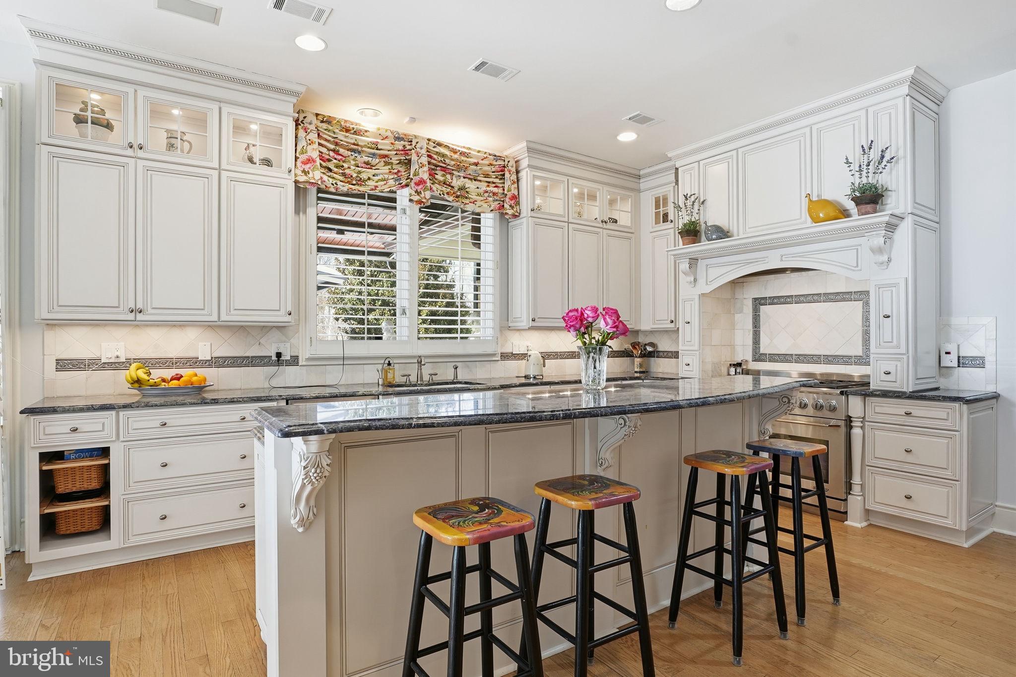 11940 River Road Potomac, MD 20854 - Photo 20 of 75 a kitchen with stainless steel appliances granite countertop a stove a sink dishwasher and white cabinets with wooden floor